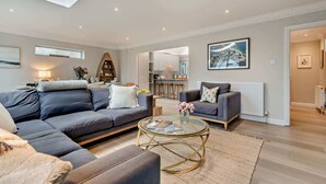 A modern living room with a sofa, coffee table, and a view into the kitchen.