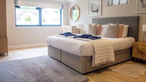A bedroom with a bed, a nightstand, a window, and a wall-mounted mirror.