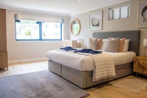 Une chambre à coucher comprenant un lit, une table de chevet, une fenêtre et un miroir fixé au mur.