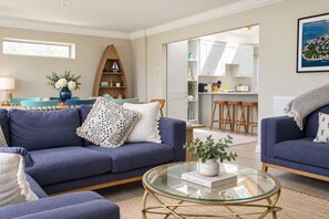 A living room with a sofa, armchairs, a coffee table, and a bookshelf.
