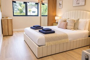 A bedroom with a large bed, a bedside table, a nightstand, a window with a view, and a wooden cabinet.