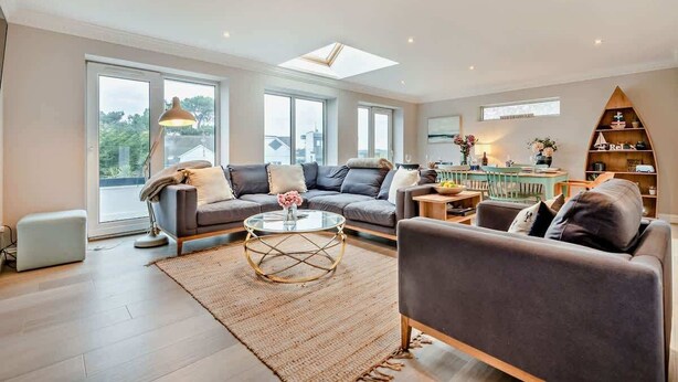 A spacious living room with a sofa, armchairs, a coffee table, and a bookshelf.
