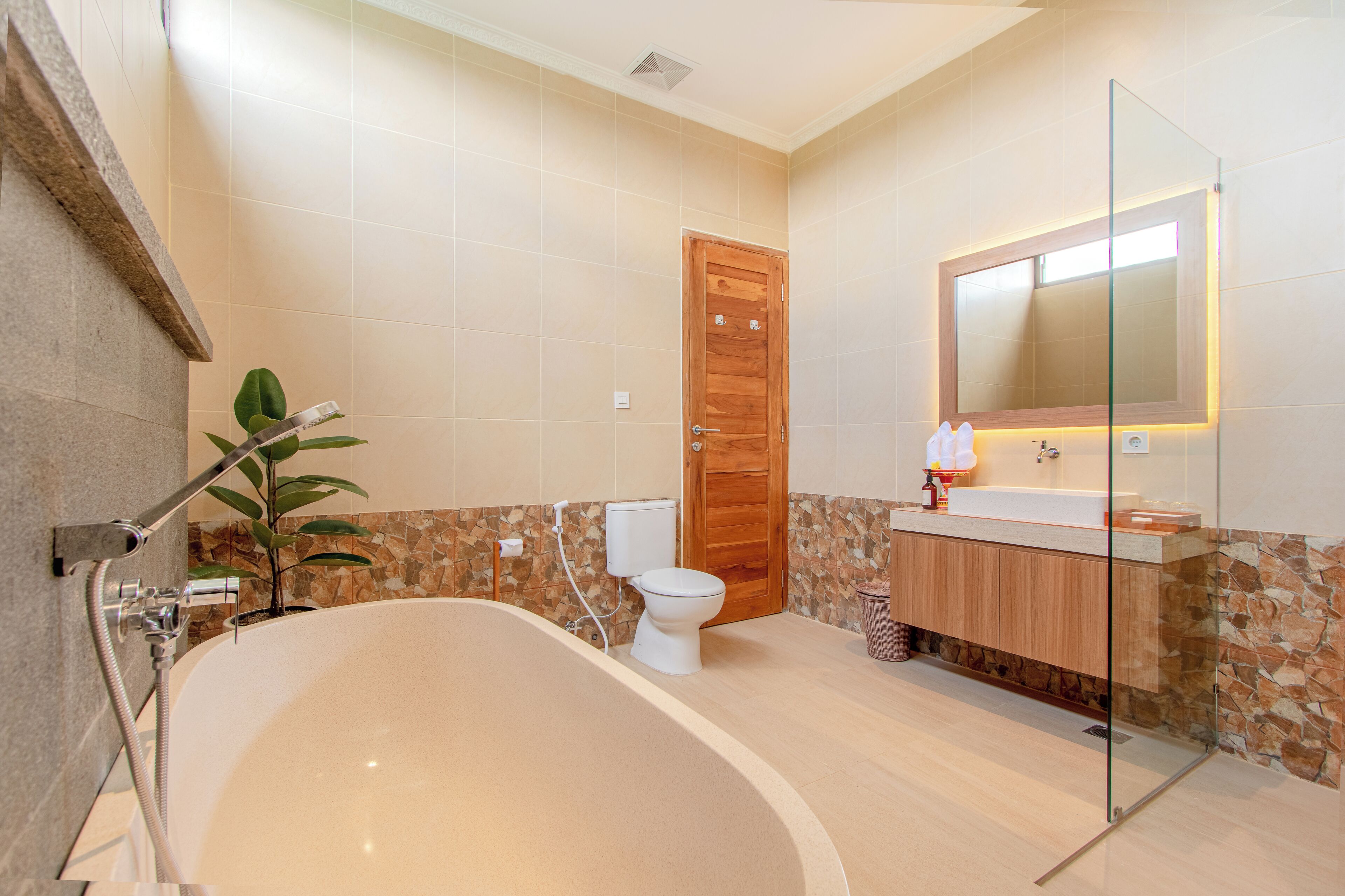 Une salle de bain moderne avec une baignoire sur pieds, une porte en bois, des toilettes et un meuble-lavabo avec un miroir.