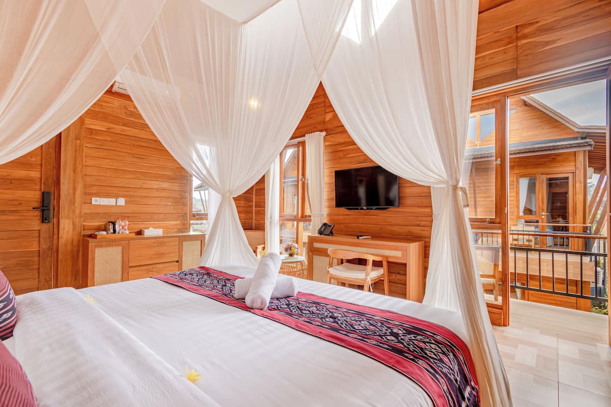 A wooden cabin bedroom with a bed, a desk, and a TV.