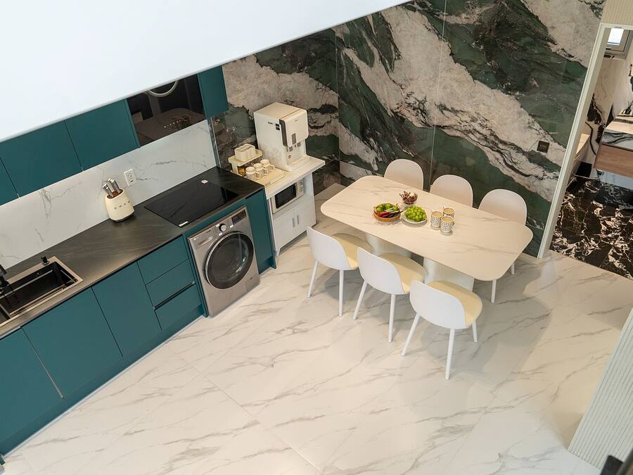 Uma cozinha moderna com máquina de lavar embutida, área de jantar com mesa de mármore e um grande painel de mármore.