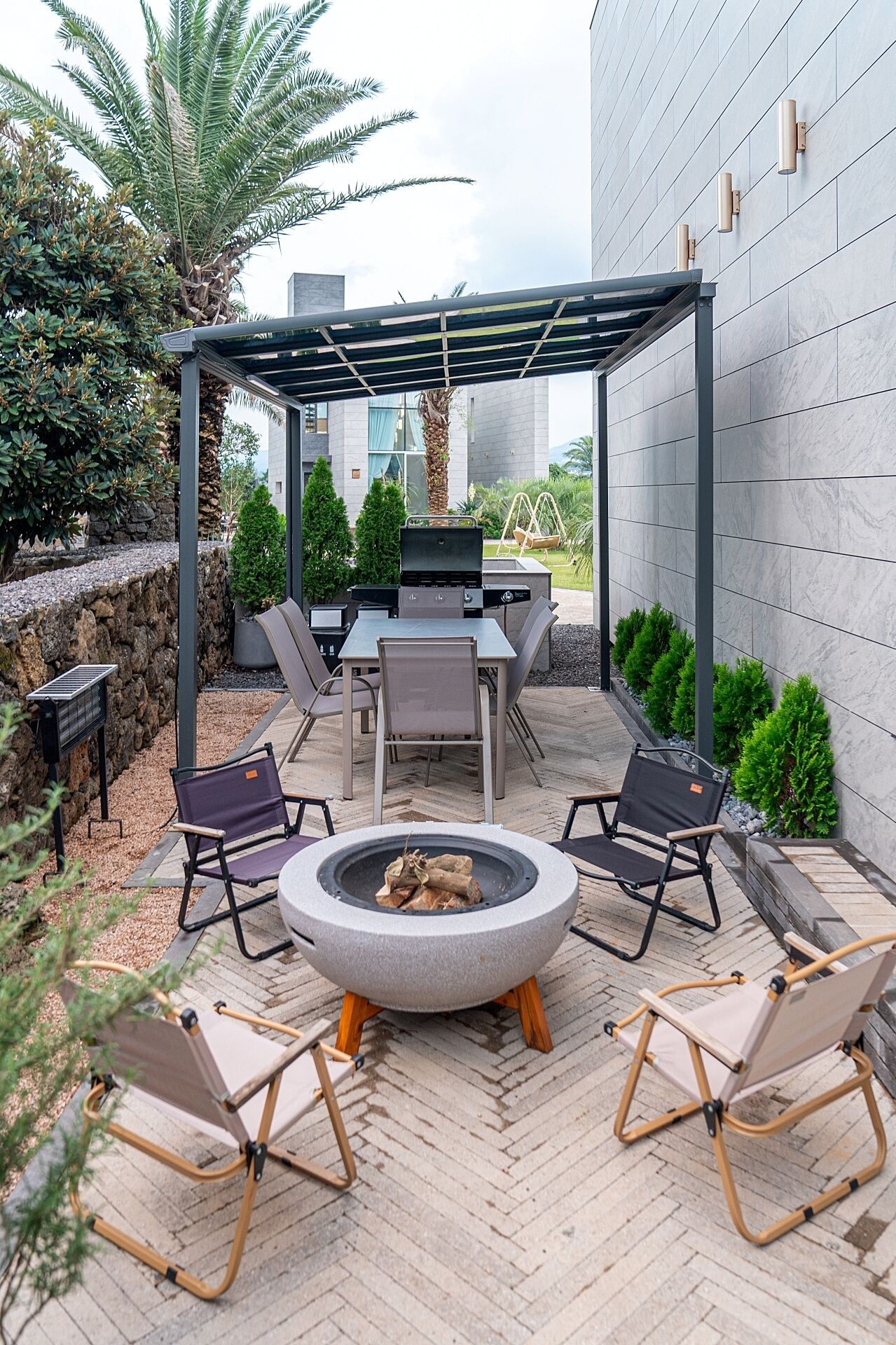 Un patio al aire libre con un hogar para fuego, asientos y una pérgola.