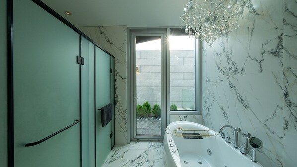 Une salle de bain moderne avec un sol en marbre, une baignoire et une grande fenêtre donnant sur un jardin.