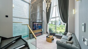 A modern living room with a large TV, a fireplace, a sofa, and a coffee table with snacks. - EUDAIMONIA (Jeju City)