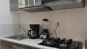 Uma cozinha equipada com micro-ondas embutido, cafeteira, liquidificador e fogão a gás.