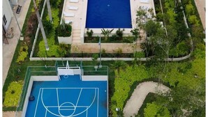 Um edifício residencial com piscina, quadra de tênis e um pavilhão com telhado de palha.