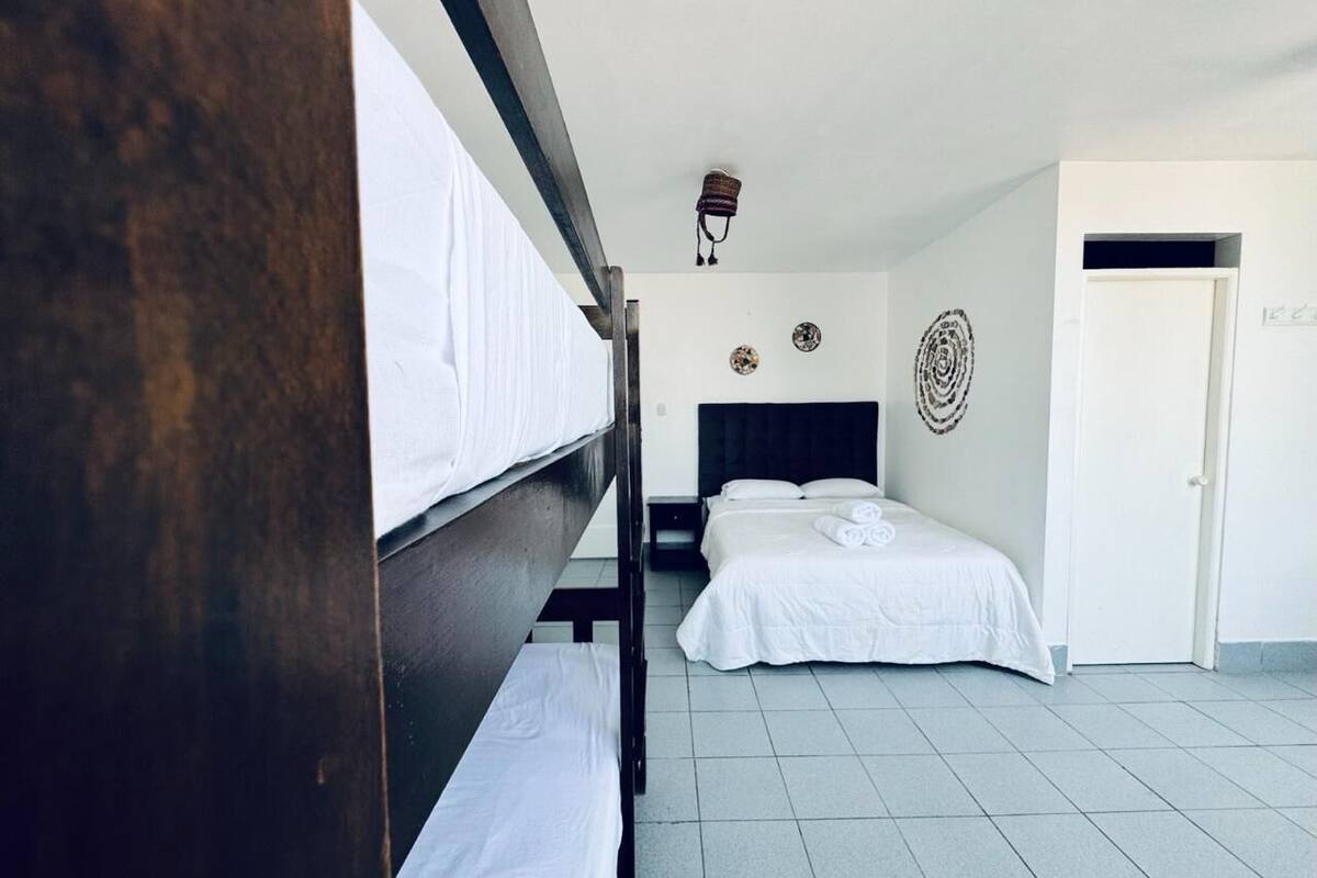 A hotel room with two beds, a dark wooden headboard, white bedding, a tiled floor, and a white door.