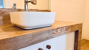 A bathroom with a white sink, wooden countertop, and two drawers. - Hotel La planicie -Pico Alto (Punta Hermosa)