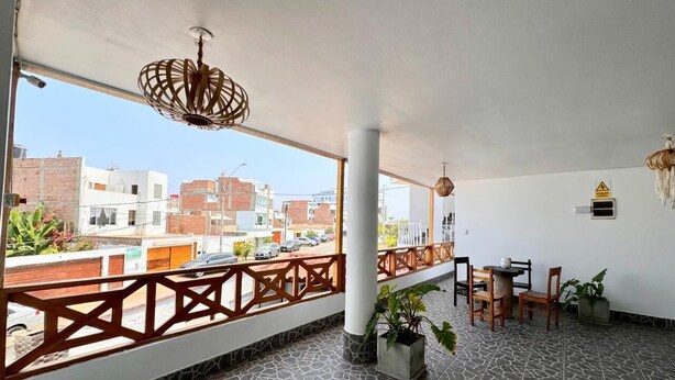 A covered outdoor area with a tiled floor, a wooden fence, and a table with chairs. - Hotel La planicie -Pico Alto (Punta Hermosa)