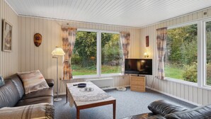 A room with a sofa, a table, a TV, and large windows. - Cozy summer house by Stevns Klint and Rødvig (Rødvig Stevns)