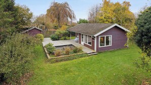 A small house with a sloped roof, a front porch, and a well-maintained garden. - Cozy summer house by Stevns Klint and Rødvig (Rødvig Stevns)