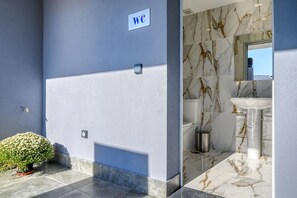 Un baño moderno con baldosas de mármol, un lavamanos y el símbolo de inodoro.