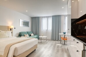 Una habitación de hotel moderna con una cama, un sofá verde, una mesita redonda y un televisor.