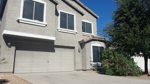 A two-story house with a garage, a driveway, and a well-maintained lawn.