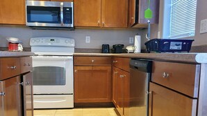 A kitchen with wooden cabinets, a microwave, an oven, and a dishwasher.