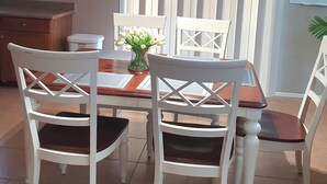 A dining area with a table, chairs, a ceiling fan, and a window with vertical blinds.
