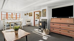A cozy living room with a fireplace, a dining area with a table and chairs, and a television on the wall. - Awesome home in Tim with WiFi (Tim)