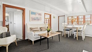 A bright, well-lit room with a striped sofa, a dining table with chairs, and a large window providing natural light. - Awesome home in Tim with WiFi (Tim)