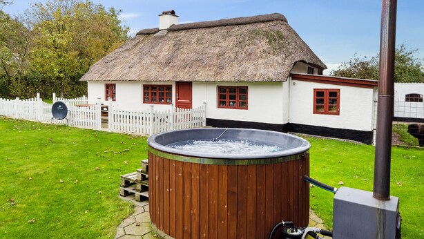 A traditional thatched-roof house with a wooden hot tub and a chimney. - Awesome home in Tim with WiFi (Tim)