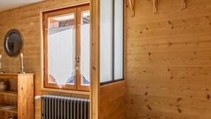 A wooden interior with a window, radiator, and wooden shelves.