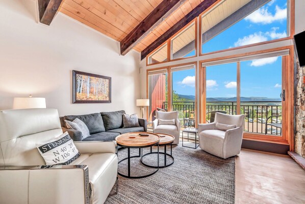 Relax in this stylish living area with a high ceiling, leather sofa, and armchair, plus a balcony with a breathtaking mountain view.
