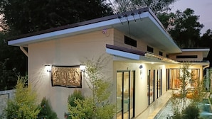 Une maison moderne avec une entrée dotée d’une porte en verre, une petite piscine et un éclairage extérieur.