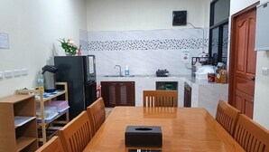 A compact kitchen with a dining area. It includes a wooden table with chairs, a refrigerator, a microwave, and a sink. - Saendee Pool Villa (Klaeng)