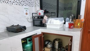 A kitchen with a microwave, gas stove, and a gas cylinder. - Saendee Pool Villa (Klaeng)