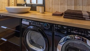 A modern kitchen with a wooden backsplash, a large sink, and built-in appliances including a washing machine and dryer. - La Duchere - 1st Floor (LA GIETTAZ)