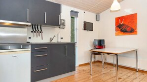 A modern kitchen with grey cabinets, a stainless steel range hood, and a wooden dining table with chairs. - Pretty Cabin in Camping Resort (Aabenraa)