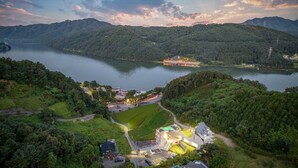 A lakeside property with a modern building, a dock, and a view of the surrounding forested hills.