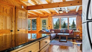 L'intérieur d'un chalet en bois comprend une cuisine, un coin repas et de grandes fenêtres.