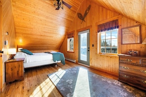 A cozy wooden cabin bedroom with a bed, dresser, and window.