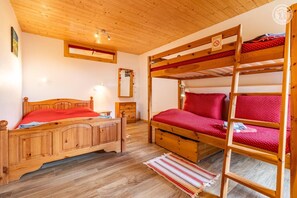 Une chambre avec un lit superposé en bois, un lit simple et une commode.