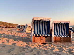 Strandkörbe mit den Nummern 2214 und 2213, vor einem Sandstrand und Dünen.
