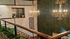 Una moderna scala con ringhiere in legno, pavimento in legno e una parete verde con motivo strutturato.