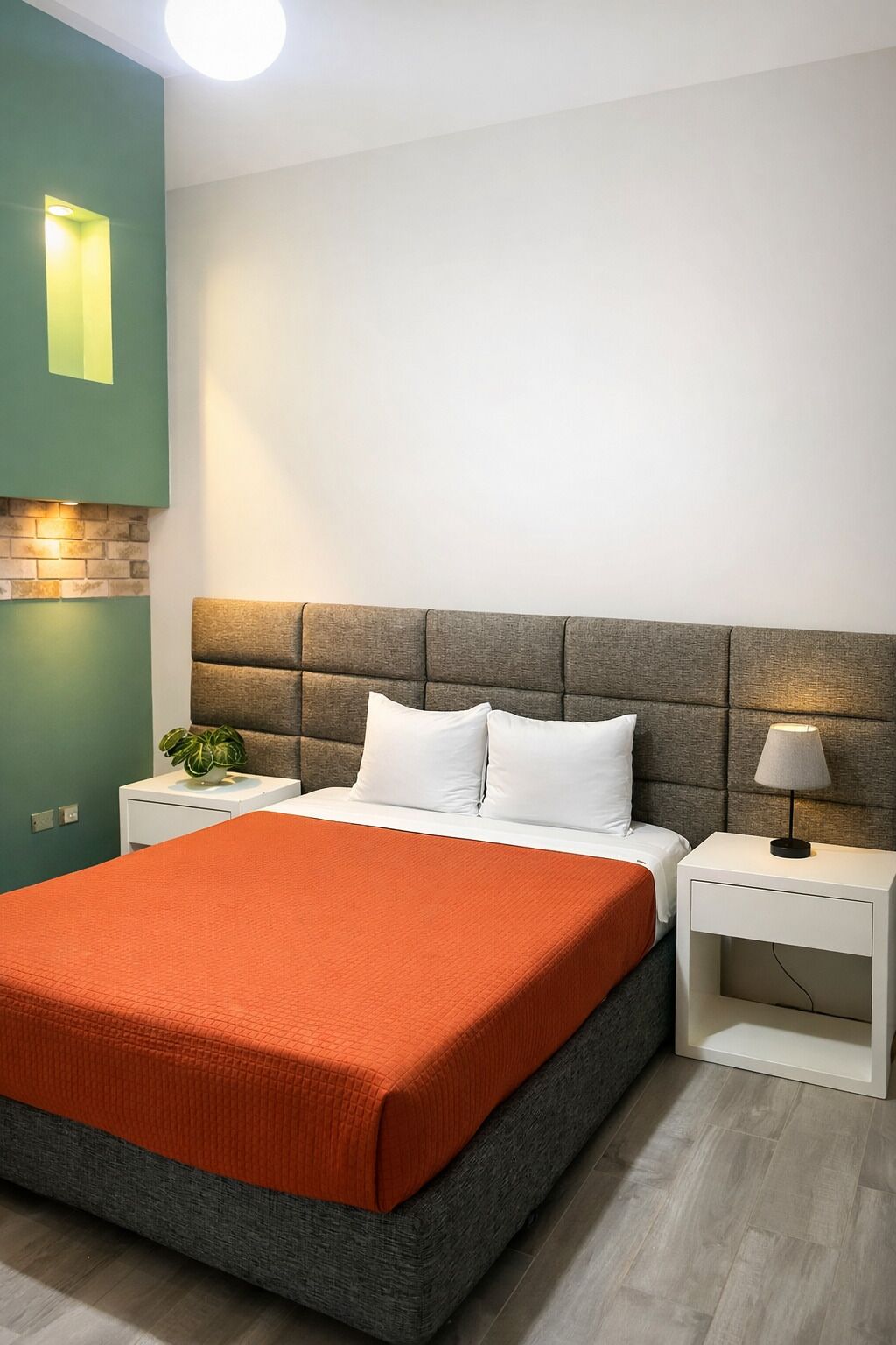 Un dormitorio moderno con cama, mesitas de noche, lámpara y una pared de acento verde.
