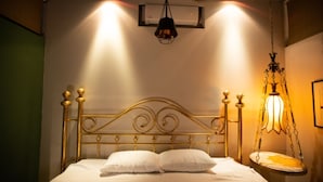 Un letto con testiera dorata, biancheria da letto bianca e una lampada a sospensione.