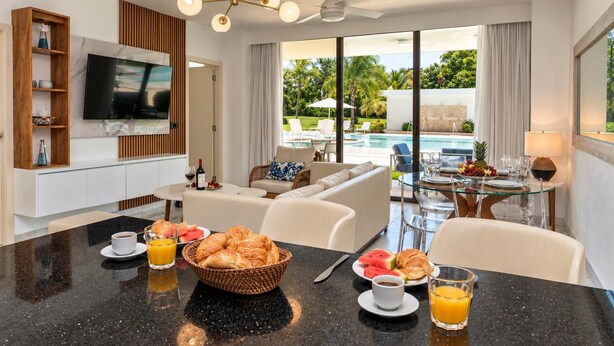 Een moderne hotelkamer met een zithoek, een televisie en uitzicht op een zwembad.