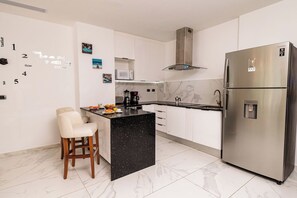A modern kitchen with a black island, stainless steel appliances, and a white marble backsplash. - Aqua Joy | 3BR Family Swim-Up + Whirlpool (Bavaro)