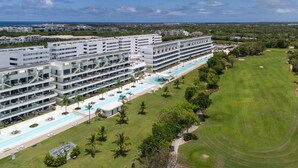 A modern hotel with multiple floors, a swimming pool, and a well-maintained lawn. - Directo piscina jardín terraza @ Cana Rock (Bavaro)