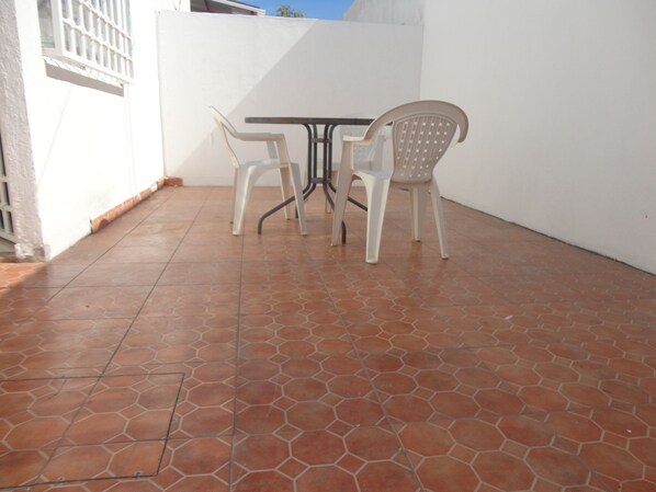 Une terrasse avec un sol carrelé, une table et deux chaises.