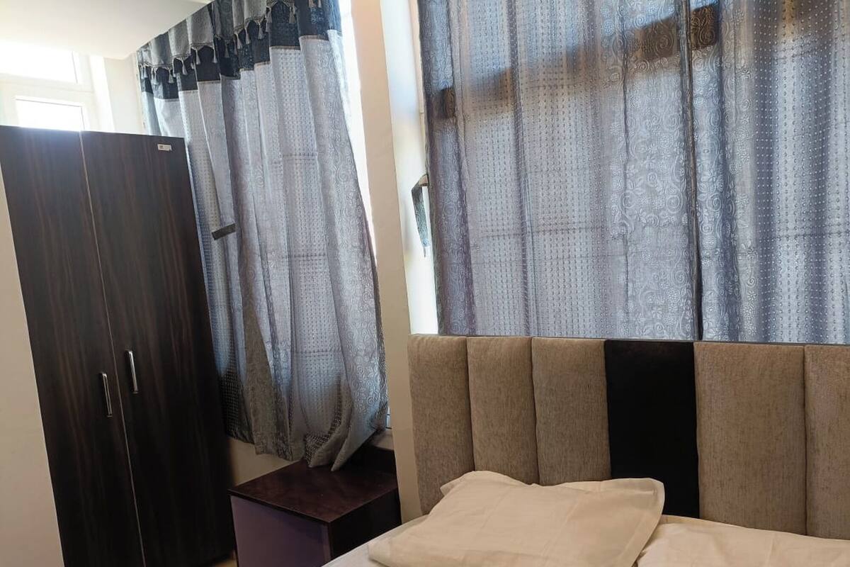 Ein Schlafzimmer mit Bett, Kleiderschrank und Vorhängen.