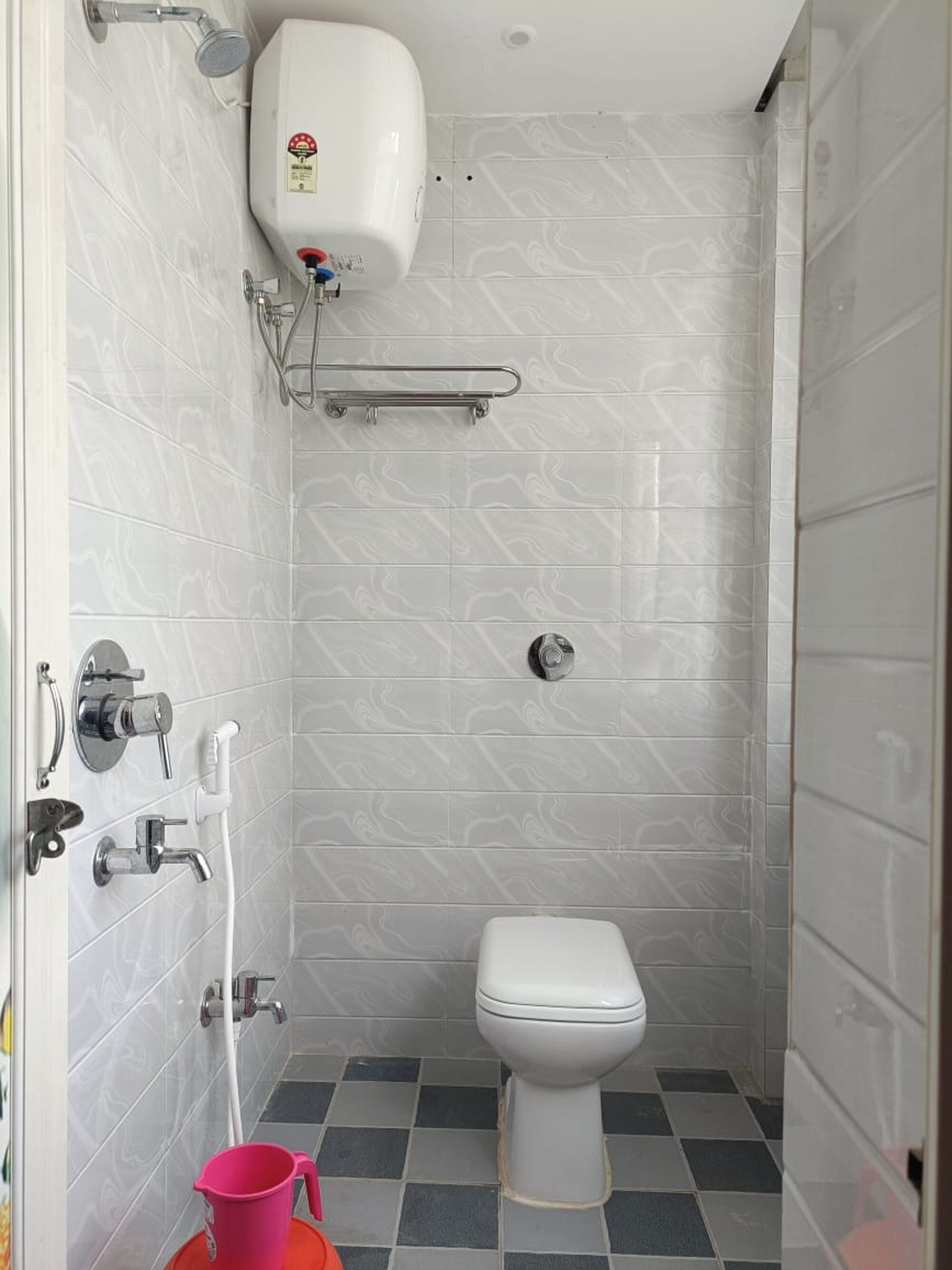 A small, modern bathroom with a toilet, a shower, and a hand dryer.
