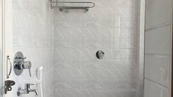 A small, modern bathroom with a toilet, a shower, and a hand dryer.