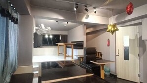 A modern living room with a black and white color scheme, a wooden dining table, a black sofa, and a star-shaped hanging light. - Arnnapurna Hotels & Resorts (Jajapur)